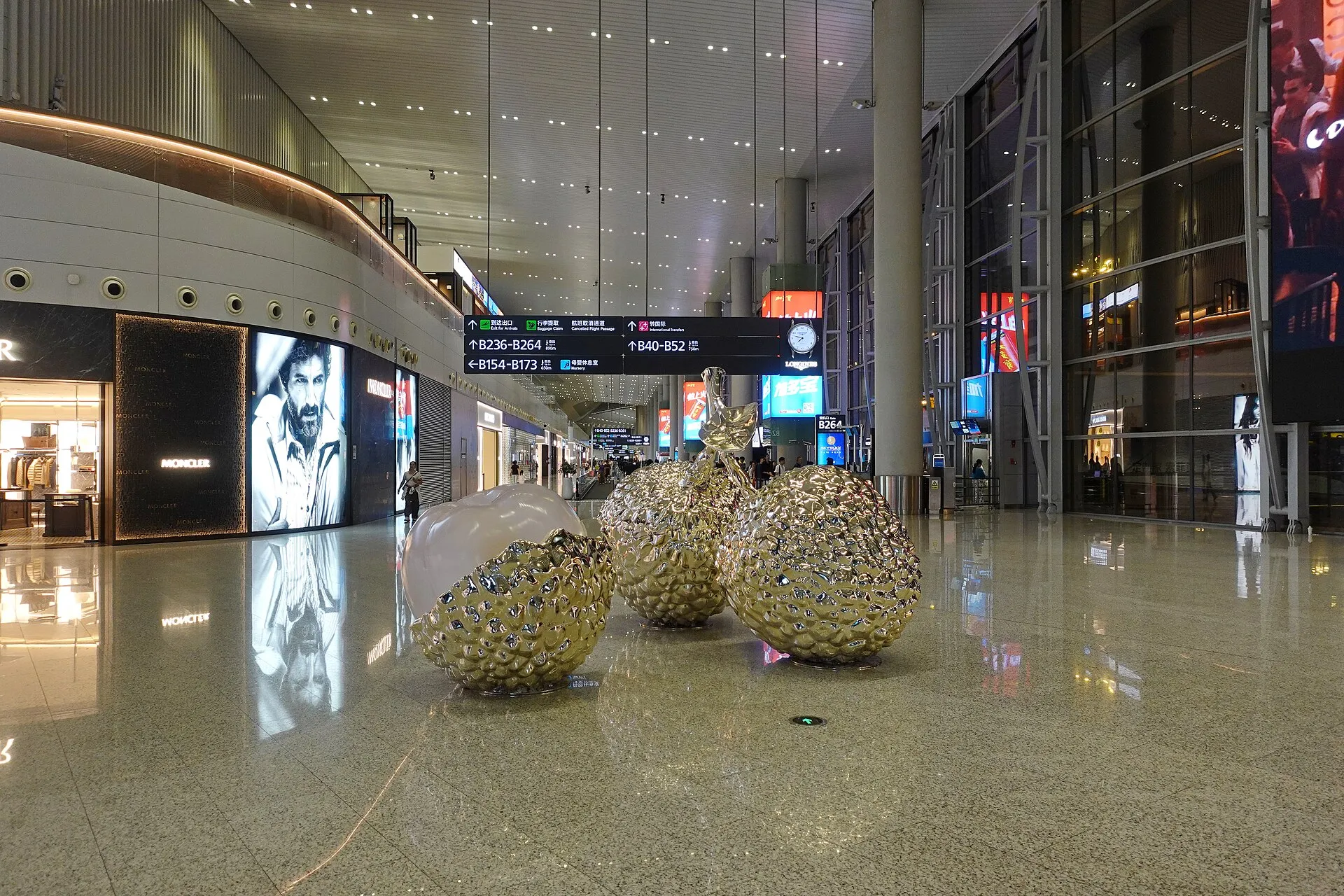Terminal 2 concourse at Baiyun Airport with signs for arrivals, baggage claim and international transfers