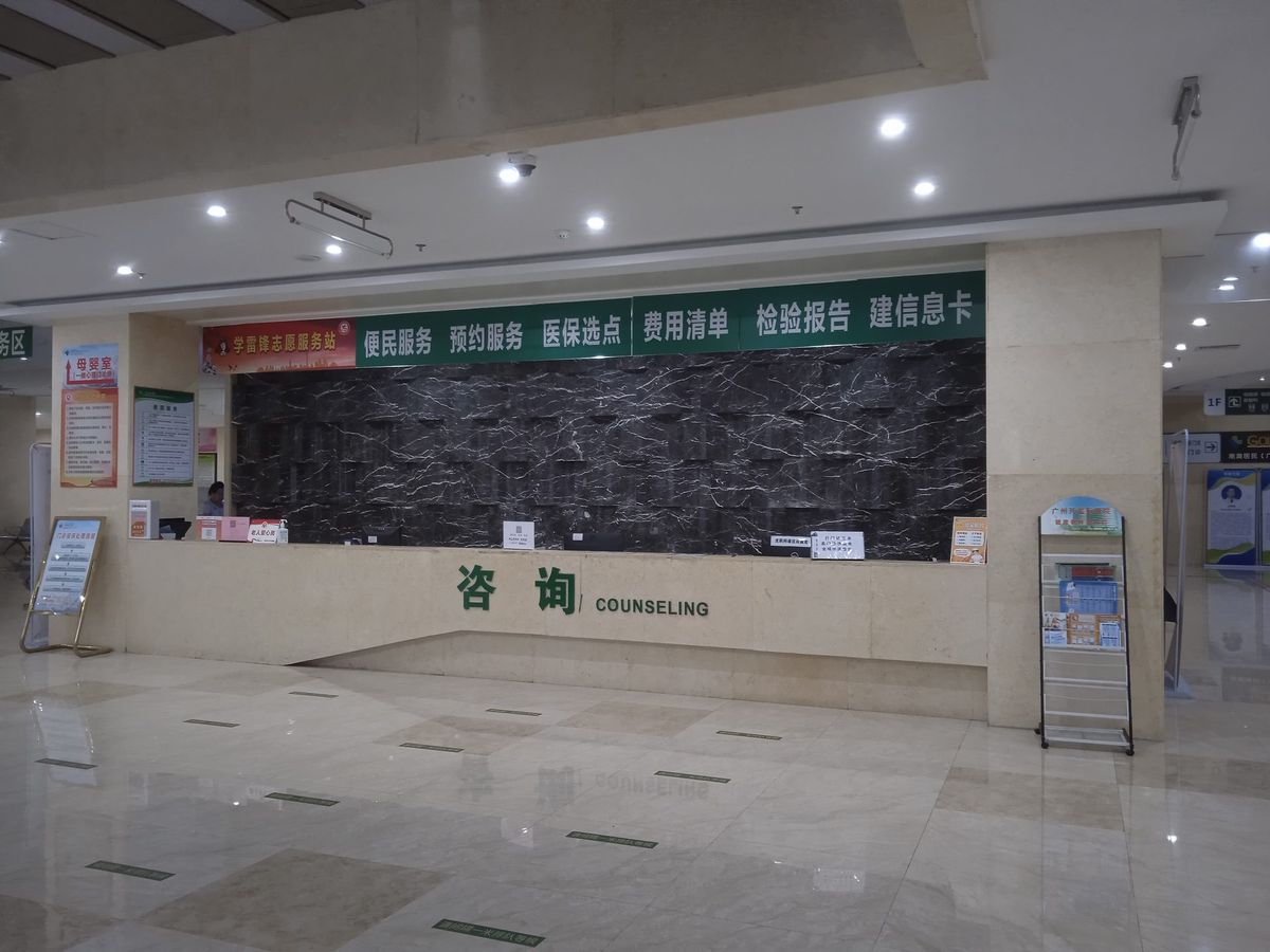 Service desk in a hospital hall in Guangzhou, with green signs above the counter and the word Counseling on it.