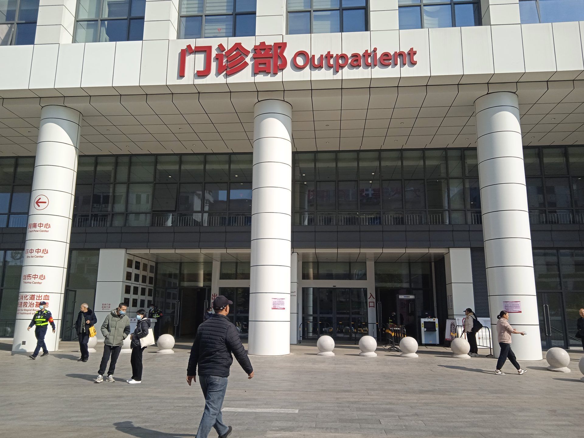 Entrance of the outpatient building of a Guangzhou hospital, with a red sign reading 门诊部 Outpatient above white columns.