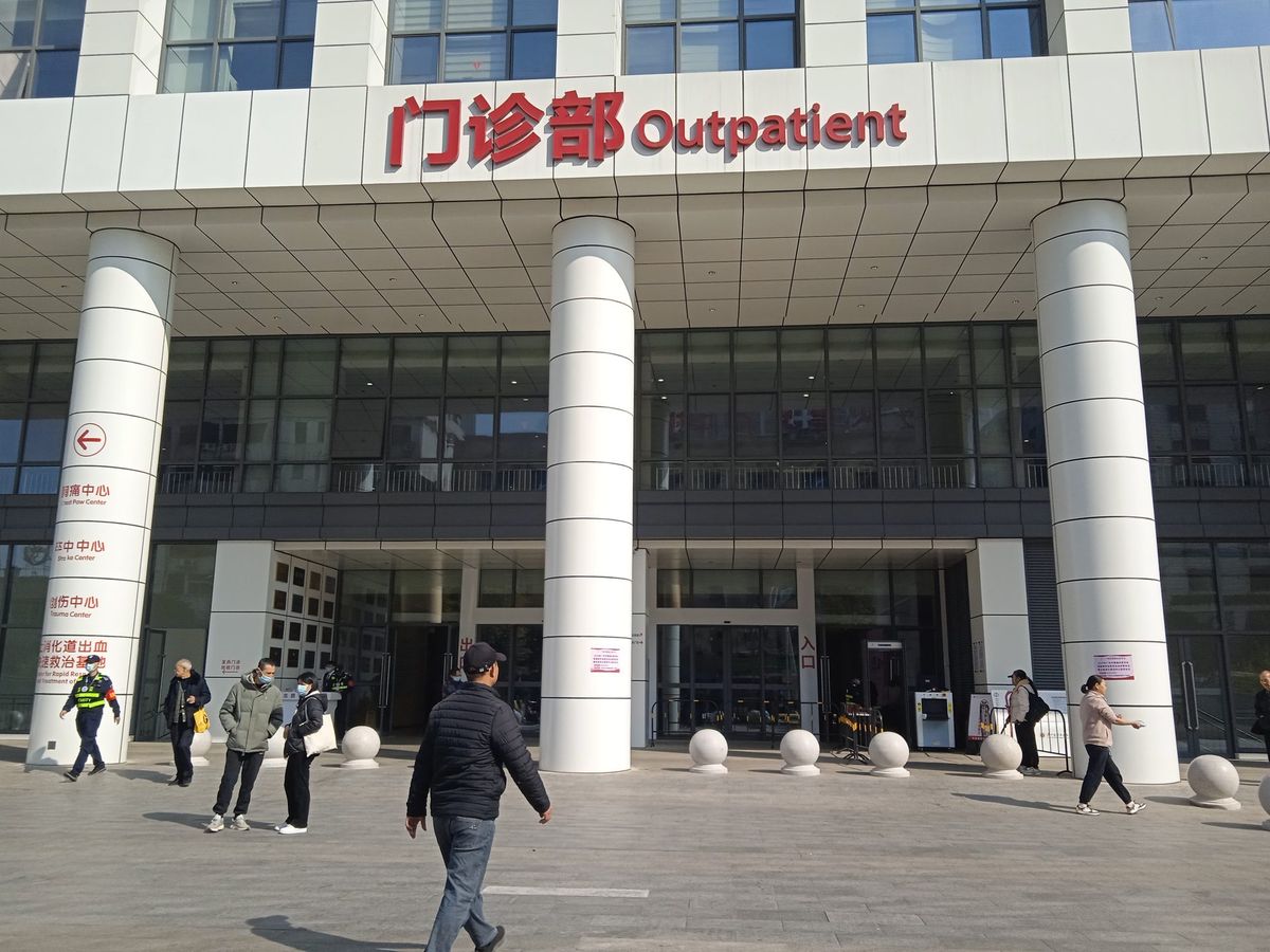 Entrance of the outpatient building of a Guangzhou hospital, with a red sign reading 门诊部 Outpatient above white columns.