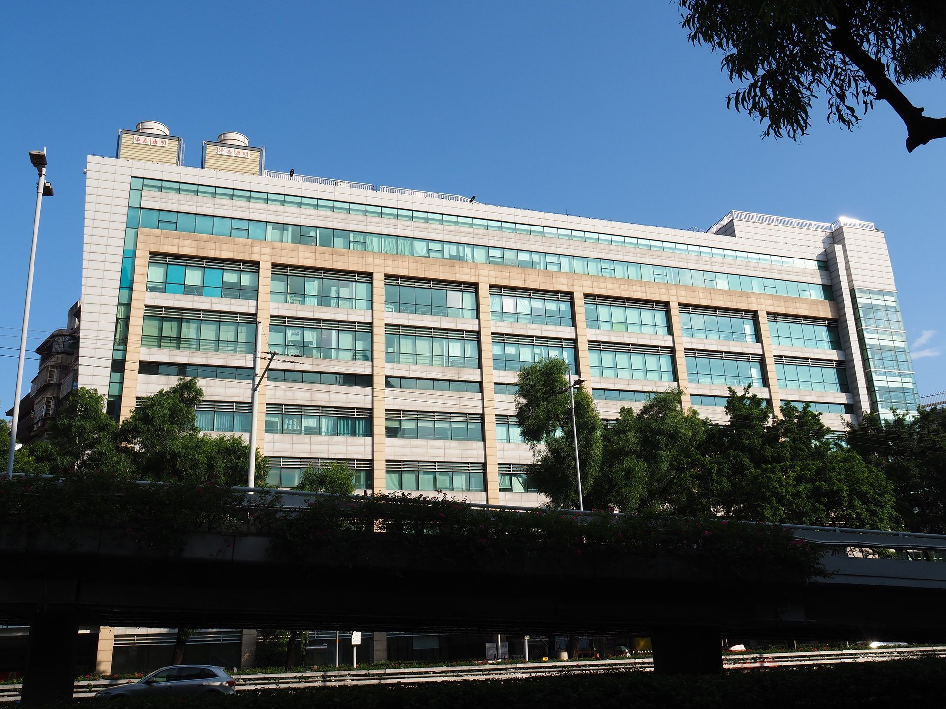 Multi-storey hospital building with a glass and stone facade, seen from the street under a blue sky, in Yuexiu District, Guangzhou.