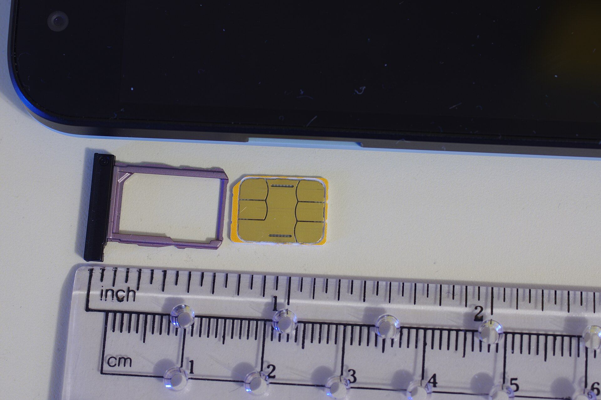 Nano SIM card and SIM tray beside a smartphone